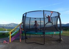 Kinder springen auf dem Trampolin auf dem Ferienhof im Allgäu